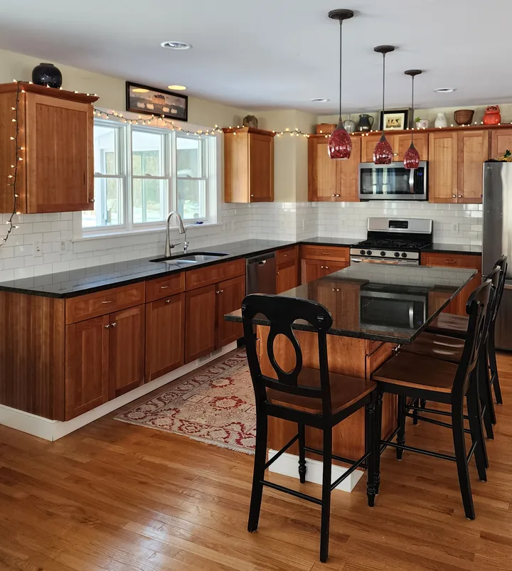 Large kitchen with wood cabinets, dark counters, and a white rectangular-tile backsplash