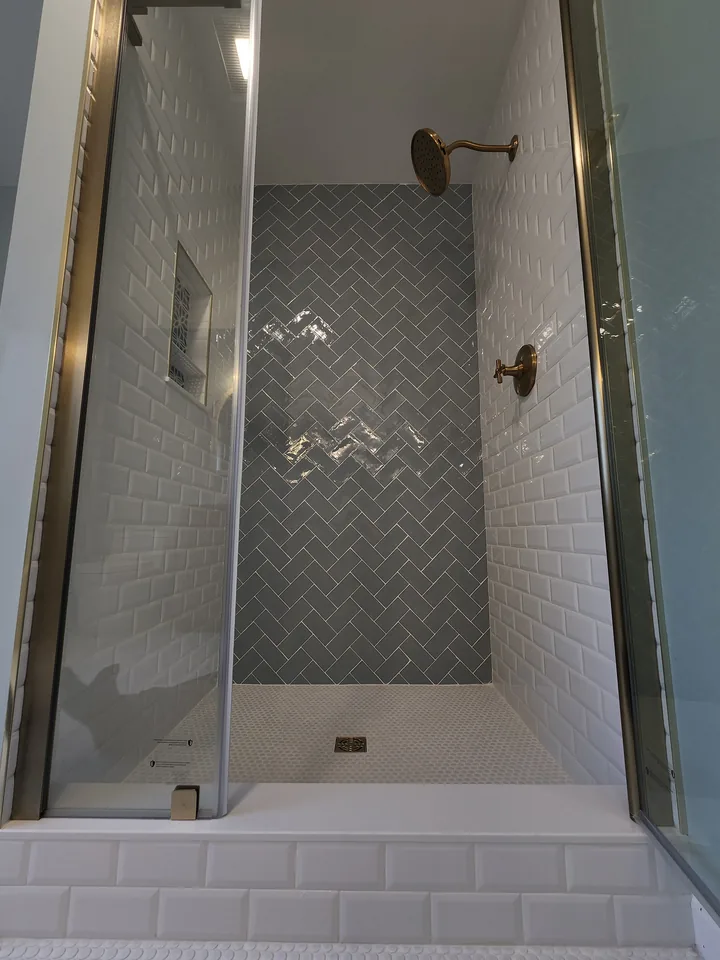 Finished glass shower with a blue-gray herringbone tile feature wall