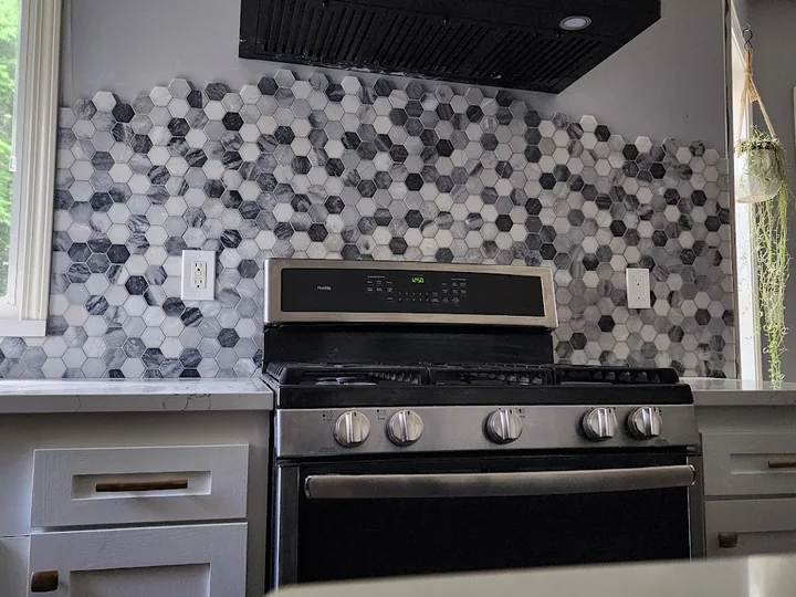 Finished gray-and-white hex mosaic backsplash behind the kitchen range
