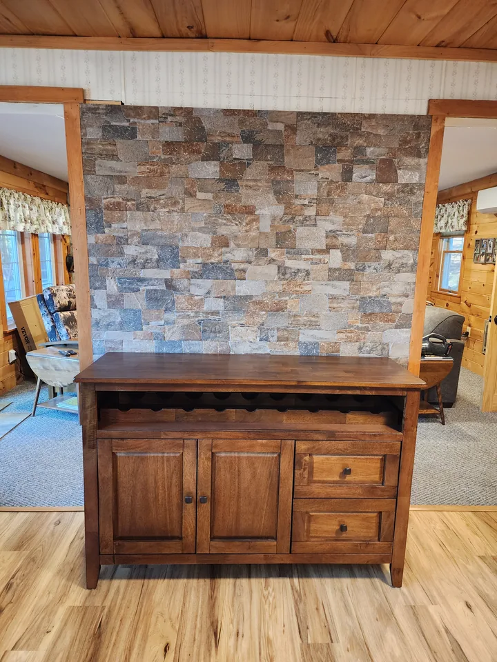 Full-height multitone stacked-format feature wall between wood-trimmed openings and behind a wood cabinet