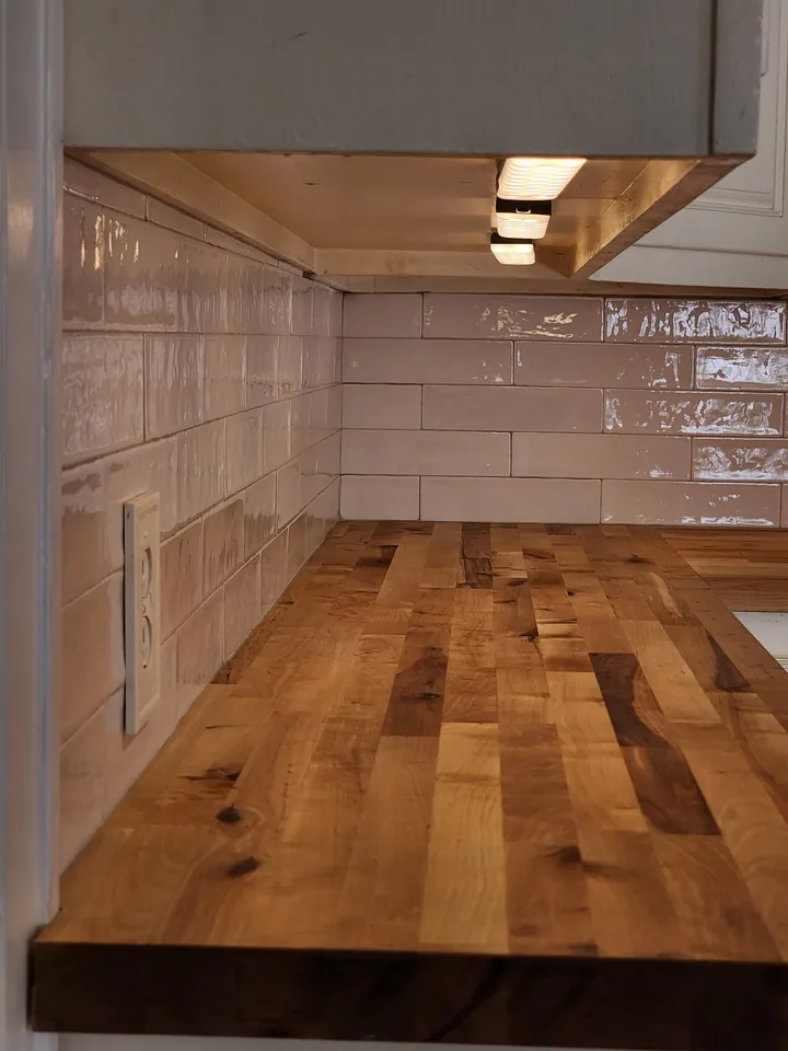 Glossy white subway tile backsplash meeting a butcher-block counter